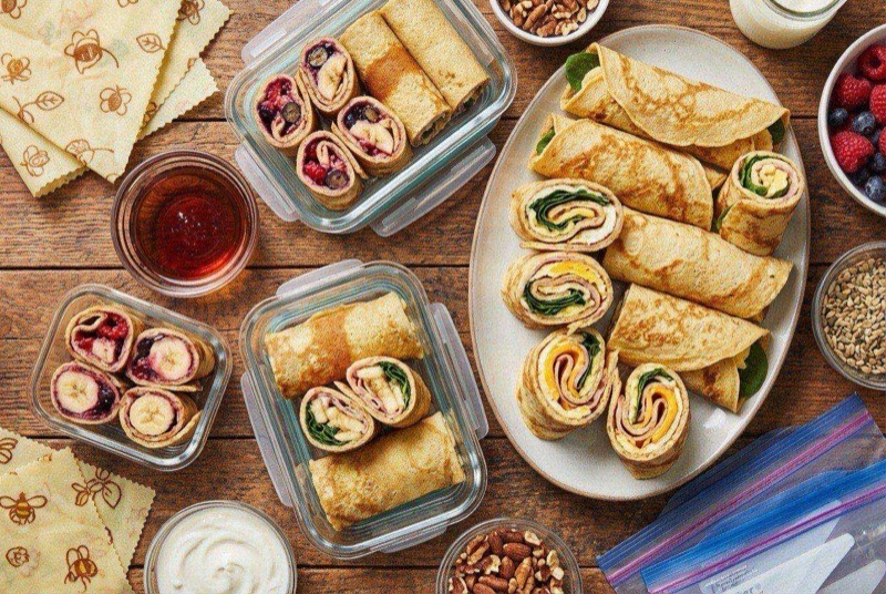 Stack of golden pancake wraps filled with sausage and cheese, some cut in half showing the filling