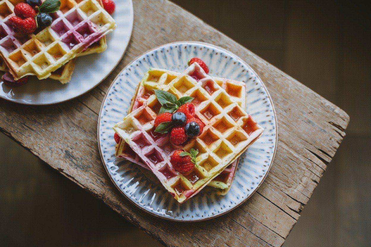 Stack of golden protein waffles with maple syrup and fresh berries on top