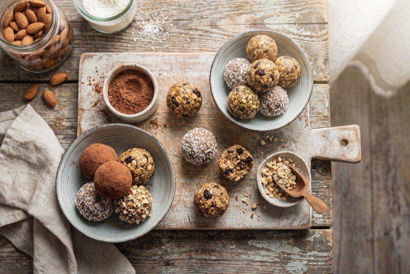 Round chocolate protein balls dusted with oats arranged on a parchment-lined plate