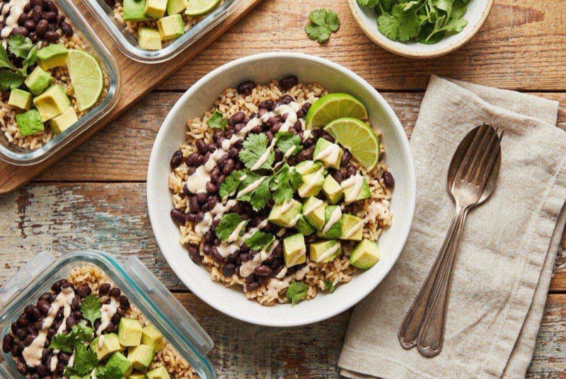 Bowl of seasoned rice topped with black beans and corn in a microwave-safe container