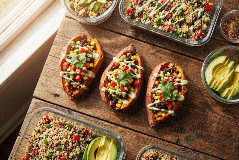 Baked sweet potato split open and stuffed with seasoned black beans and corn, topped with green avocado crema and crumbled white cheese